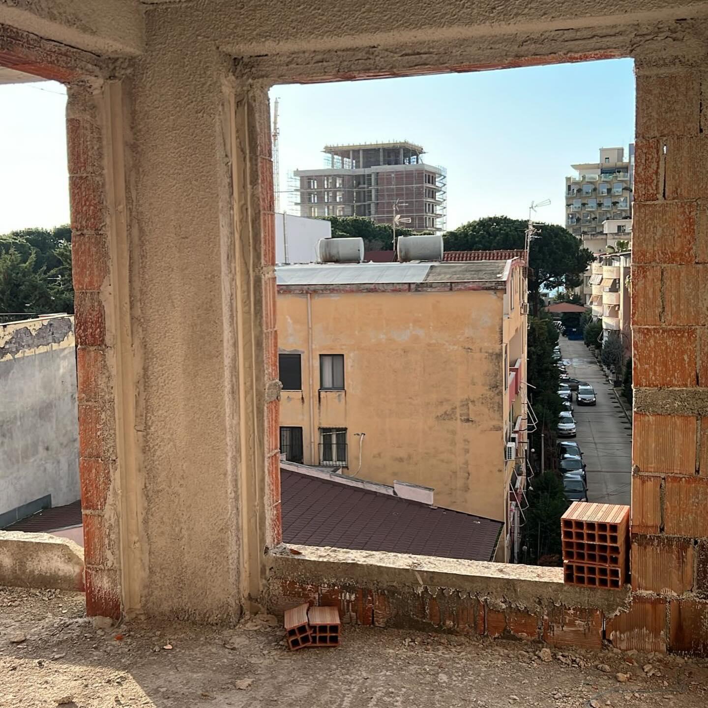View through an unfinished window opening on site, looking out over the neighbourhood rooftops.