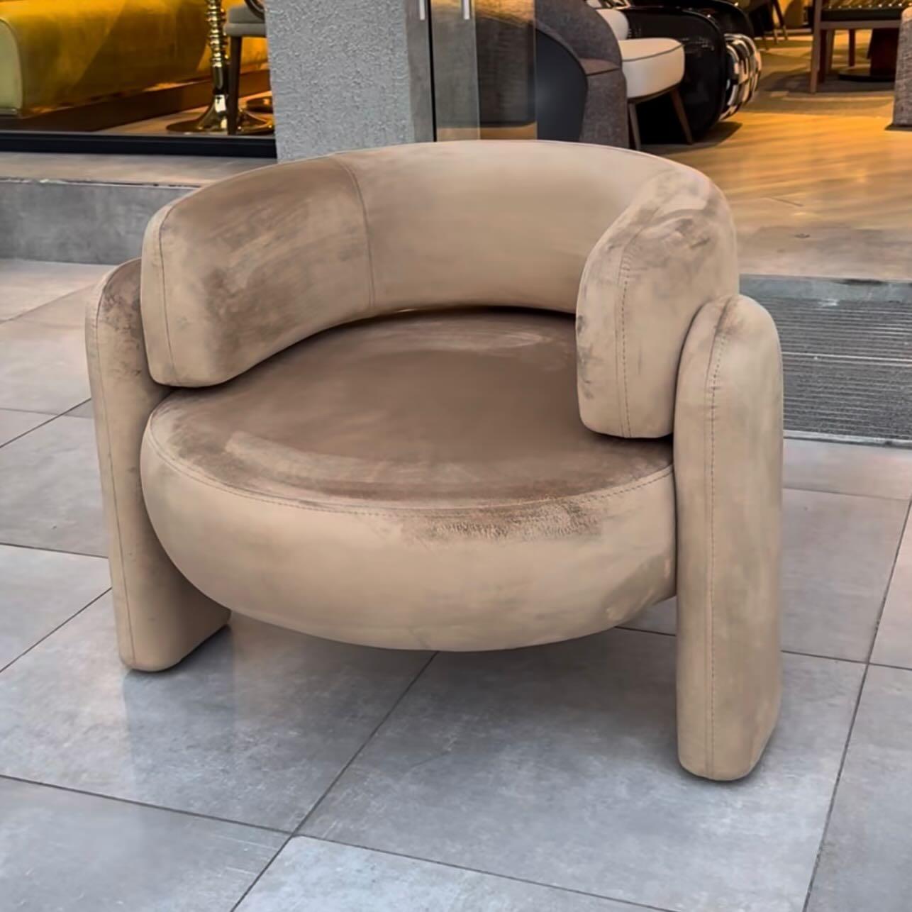 Rounded lounge chair upholstered in camel velvet.