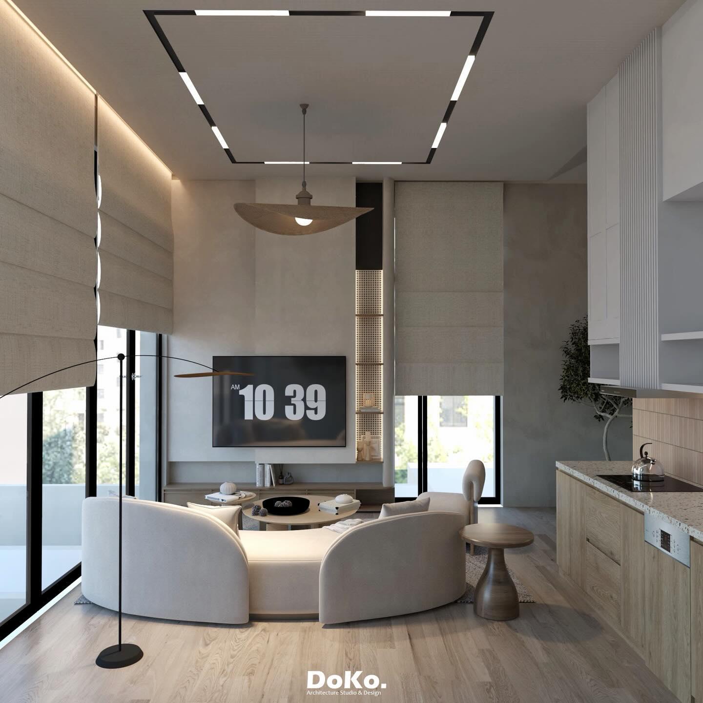 Living area with linear ceiling lights, a timber pendant, the curved sofa and a timber kitchen to the side.