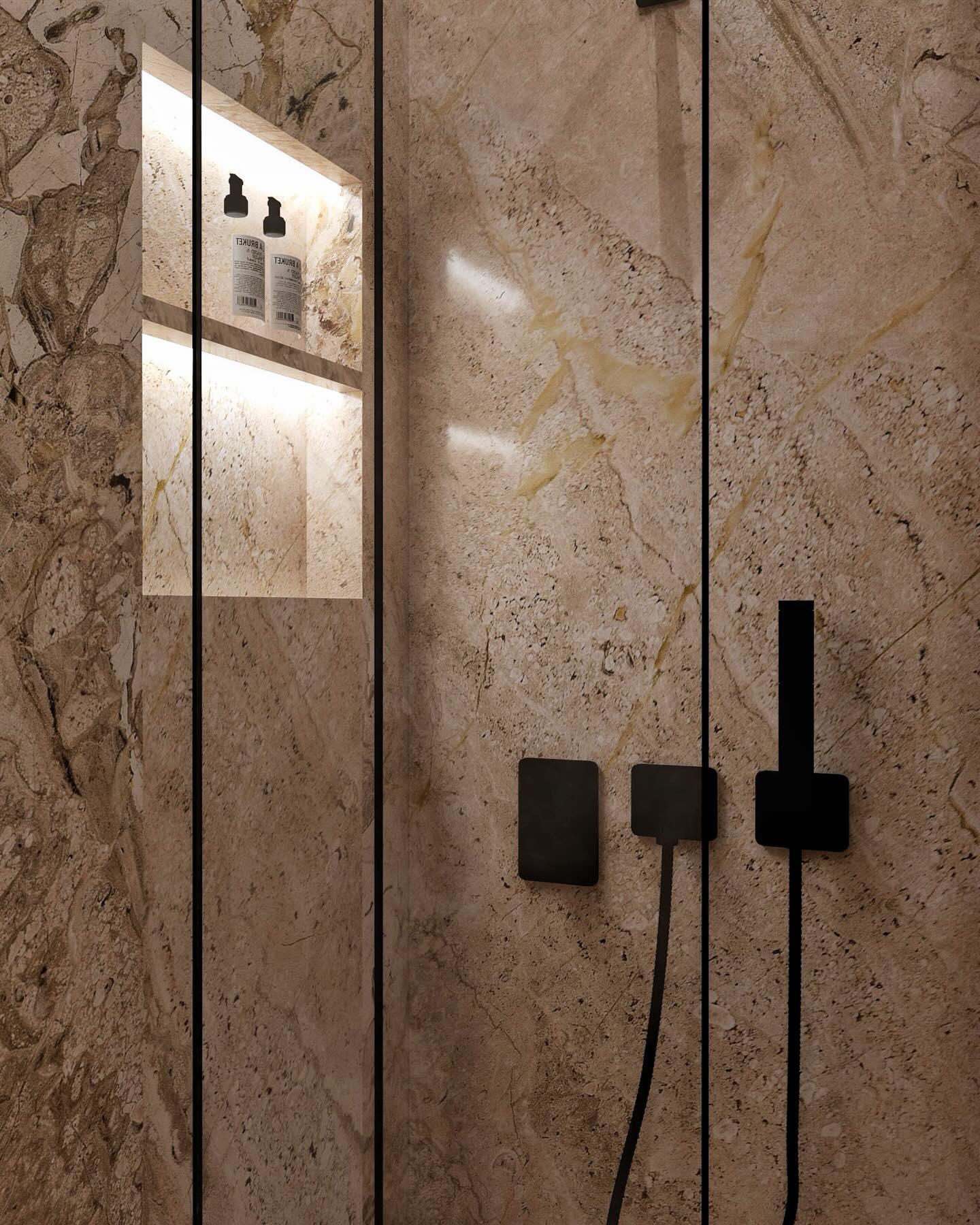 Detail of the marble shower wall with a lit recessed niche and matte black controls.