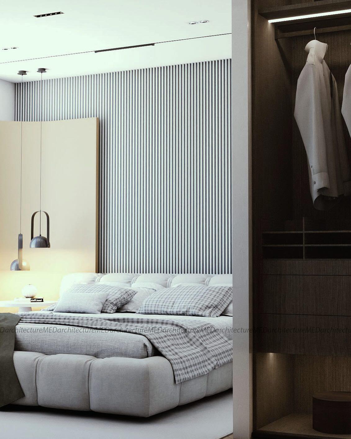 Bedroom with fluted wall panels, an upholstered bed, a bedside lamp and a wardrobe with glass doors.