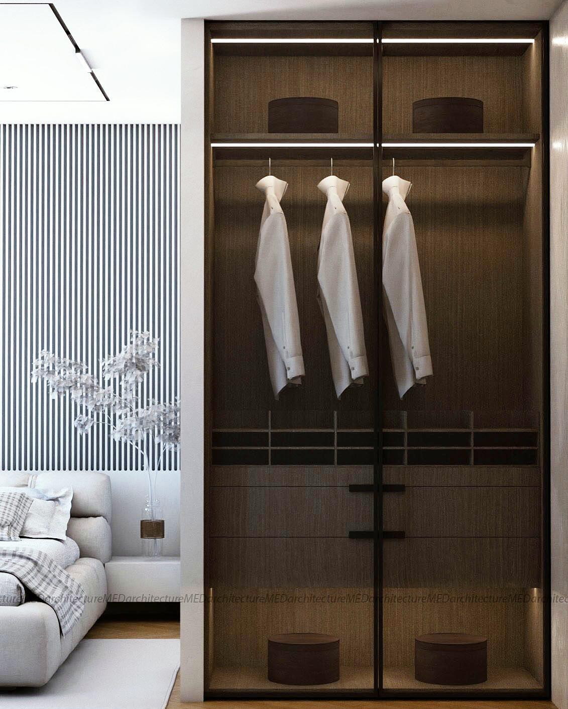 Wardrobe in dark timber and glass with integrated lighting and hanging rails.