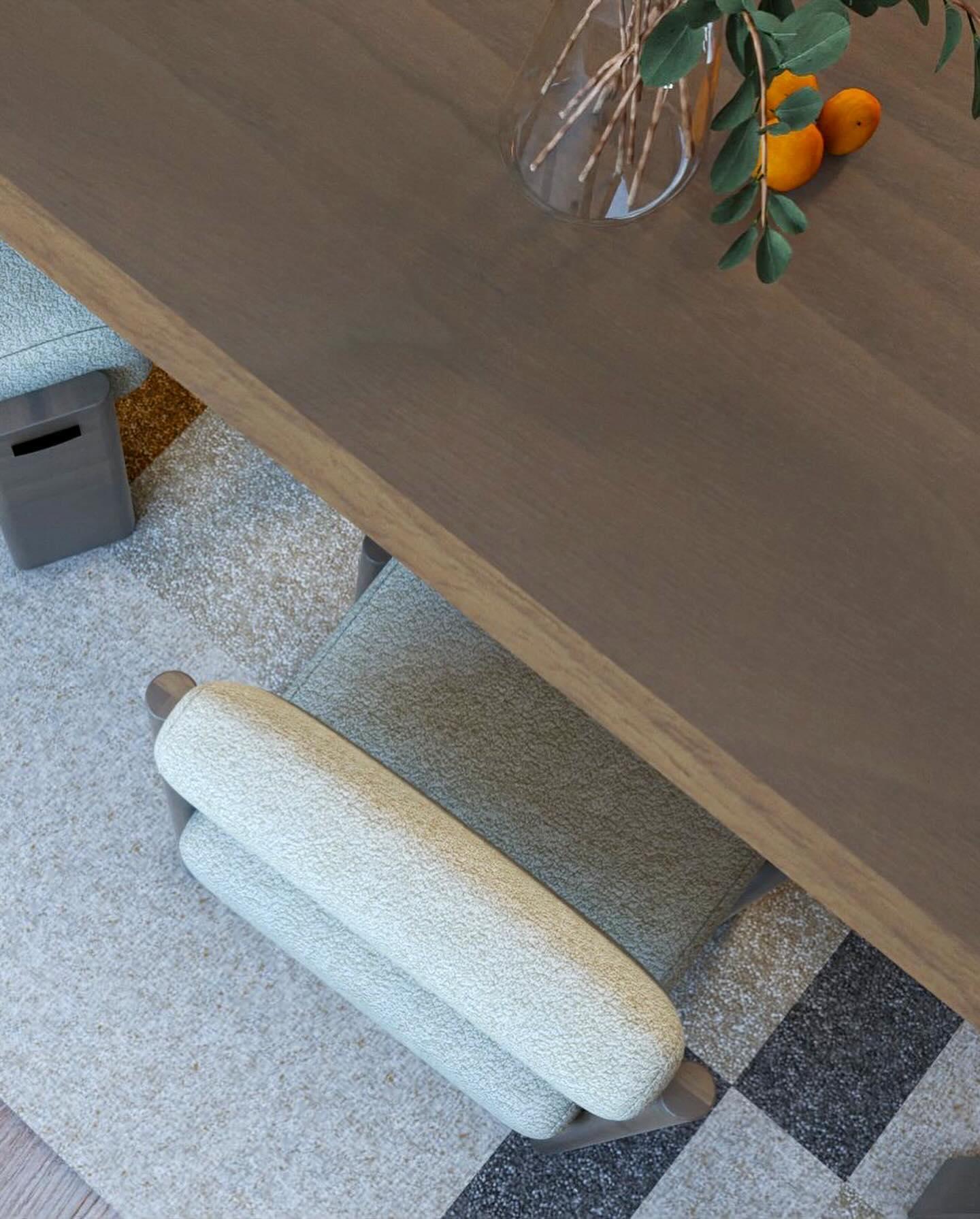Top-down view of the dining table and an upholstered chair on a grey rug.