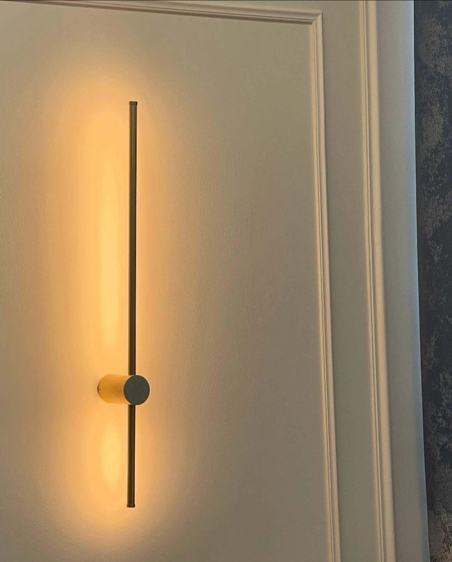 A linear wall light glowing against the panelled wall.